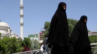 Women walk in front of a mosque