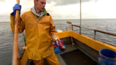 Fisherman picks plastic bottle out of the sea