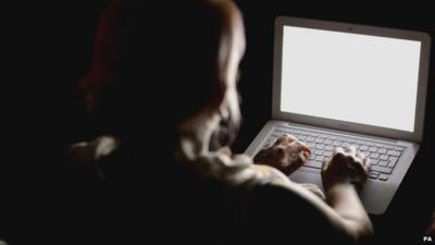 Silhouette of woman about to type on a laptop screen (nothing visible on screen)