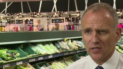 Tesco boss Dave Lewis standing in front of some vegetables