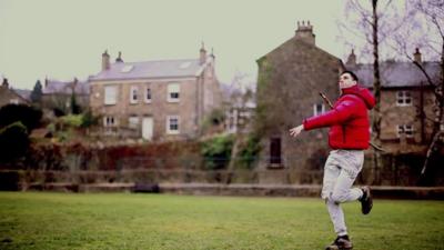 Man throwing a stick in a park like it's a javelin