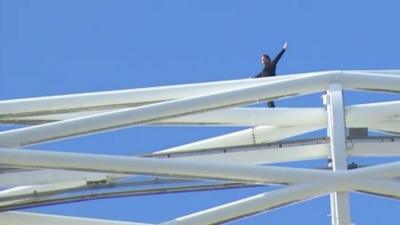 Parkour specialist James Kingston standing on top of the Wembley Arch with his arms spread out