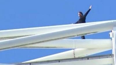 Parkour specialist James Kingston standing on top of the Wembley Arch with his arms spread out