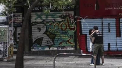 Youths hug outside closed shop in Athens