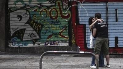 Youths hug outside closed shop in Athens