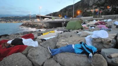 People sleeping on rocks at border between Italy and France