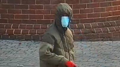 The suspect in a green coat and blue face mask