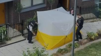 Police surround a white and yellow tent on New Union Close