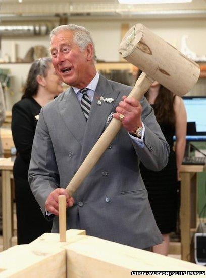 Prince Charles hammers in a peg with a giant mallet