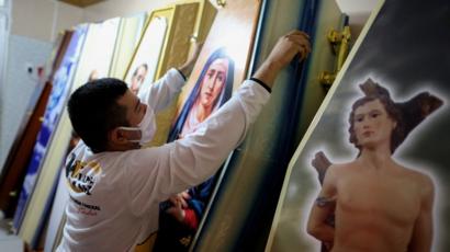 Empleado de una casa de funerales acomoda los féretros.