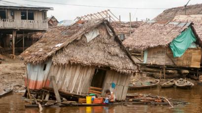 Casas de madera se derrumban sobre el agua.