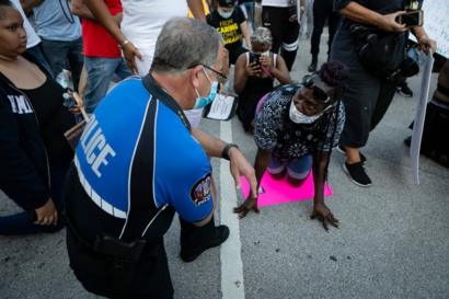 Un policía arrodillado junto a una manifestante