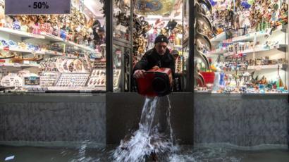 Un commerçant utilise un seau pour retirer l'eau de sa propriété à Venise, 13 novembre 2019