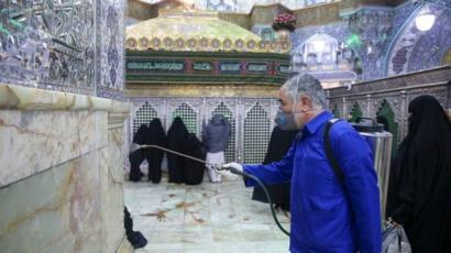Petugas menyemprotkan disinfektan di kuil Hazrat Masumeh di kota Qom