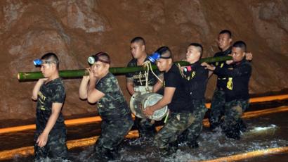 Homens de equipe de resgate carregam equipamento nos arredores de caverna