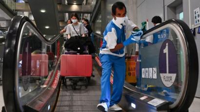 A worker wearing a protective facemask cleans the handrails at the passengers' arrival area of Suvarnabhumi Airport in Bangkok