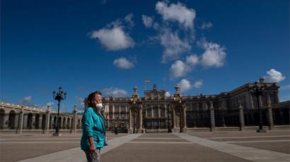 A woman walks in front of the Royal Palace in Madrid on May 10, 2020 during the hours allowed by the government to exercise