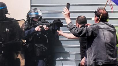 شرطي يصوب بندقية رصاص مطاطي على متظاهر