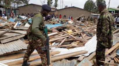 Police officers stand on the debris of a collapsed school classroom