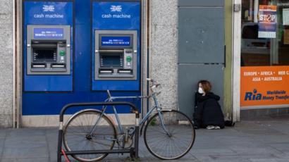 Mujer con mascarilla al lado de un cajero automático