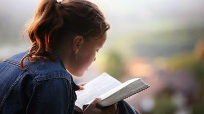 A young woman intently reading a book