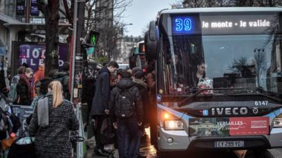 Commuters get on a bus