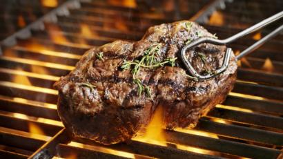 A beef steak over a flame grill