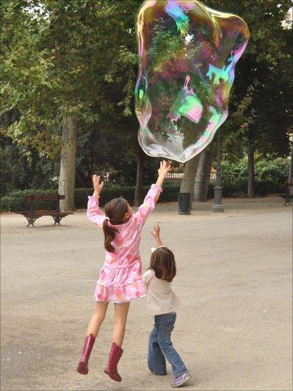 Two girls jumping up to touch a bubble