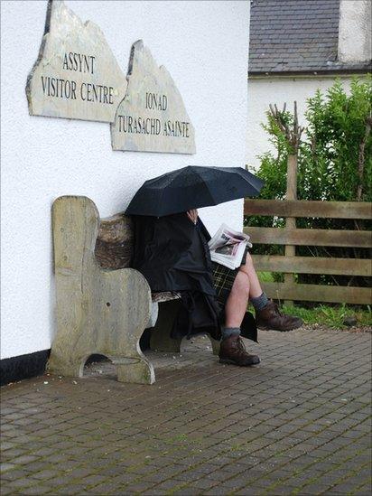 Man reading newspaper in Lochinver in the Highlands