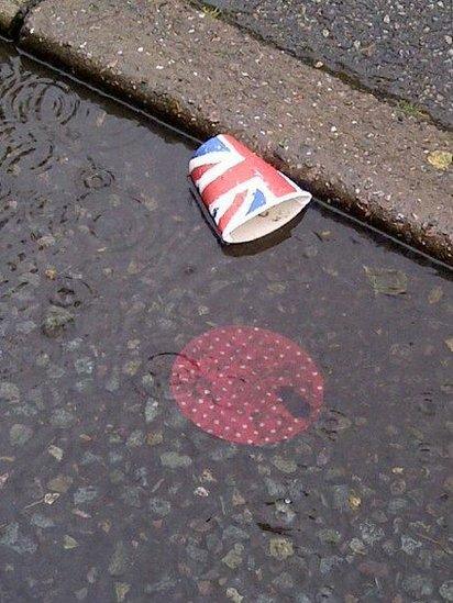 A paper cup in a puddle of rain