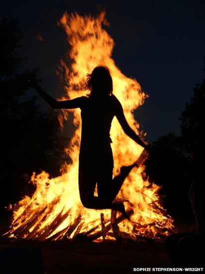 Silhouette of a person in front of a bonfire