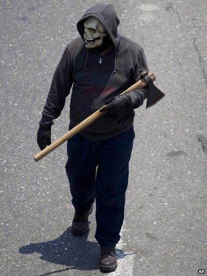 Protester carrying an axe and wearing a skeleton mask marches against education reform on 18 April 2013