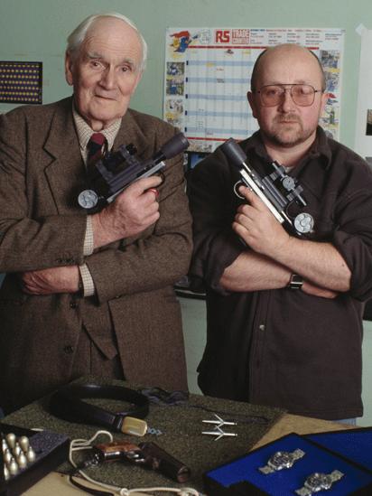 Desmond Llewelyn with special effects technician Nicholas Finlayson, and some of the props from the James Bond film GoldenEye, 1995
