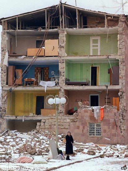 A woman stands near a destroyed building, on December 15, 1988, in the devastated town of Leninakan, after an earthquake hit Armenia, on December 7, 1988.