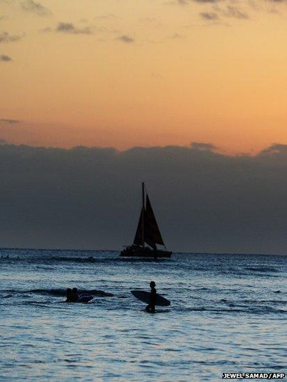 A man wades in the water at sunset in Honolulu, Hawaii