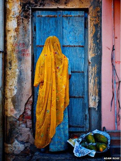 A woman dressed in traditional garb returns home from a street market
