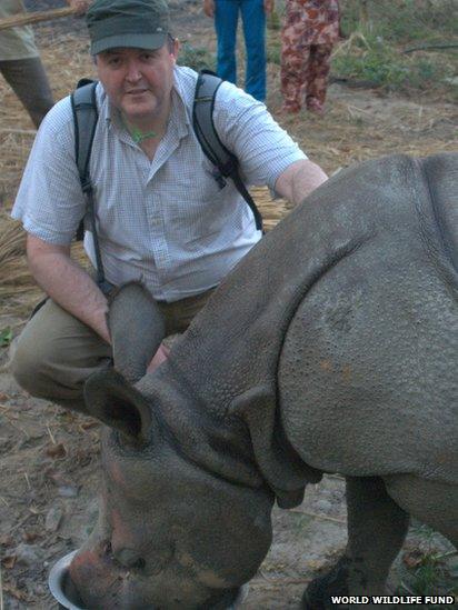 Crawford Allan kneeling next to baby rhino