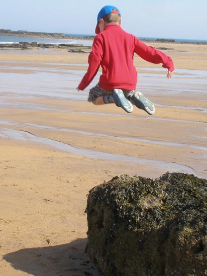 Boy jumping off a rock