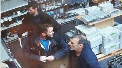 A CCTV image of three men in dark clothing in a hardware store 