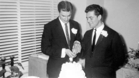 Two men cut wedding cake