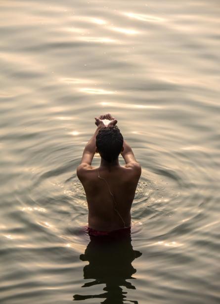 Un hombre tomando un baño ritual en el río Ganges durante el alba invernal