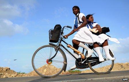 Schoolgirls ride a bicycle in Jaffna