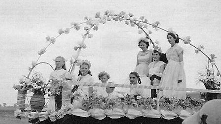Greyscale image of a young May Queen being crowned beneath a canopy of flowers