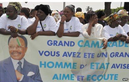Women hold poster depicting the late President Omar Bongo at Libreville airport on 11 June 2009
