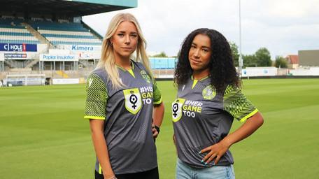 Two women wearing football shirts looking at camera