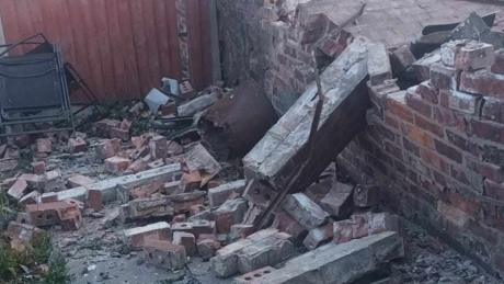 Bricks and rubble on the ground next to a partially-collapsed wall.