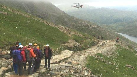 Rescuers carry a stretcher towards as a rescue helicopter hovers above