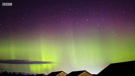 The aurora borealis visible over rooftops.