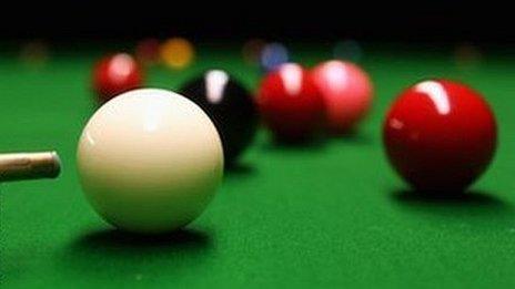 close up of a cue about to hit a white ball on a snooker table