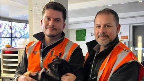 Mr Hug and Mr Timmins hold the puppy after rescuing it from the tracks
